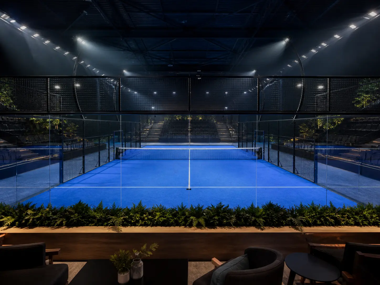 Cancha de padel de noche con gradas e iluminacion